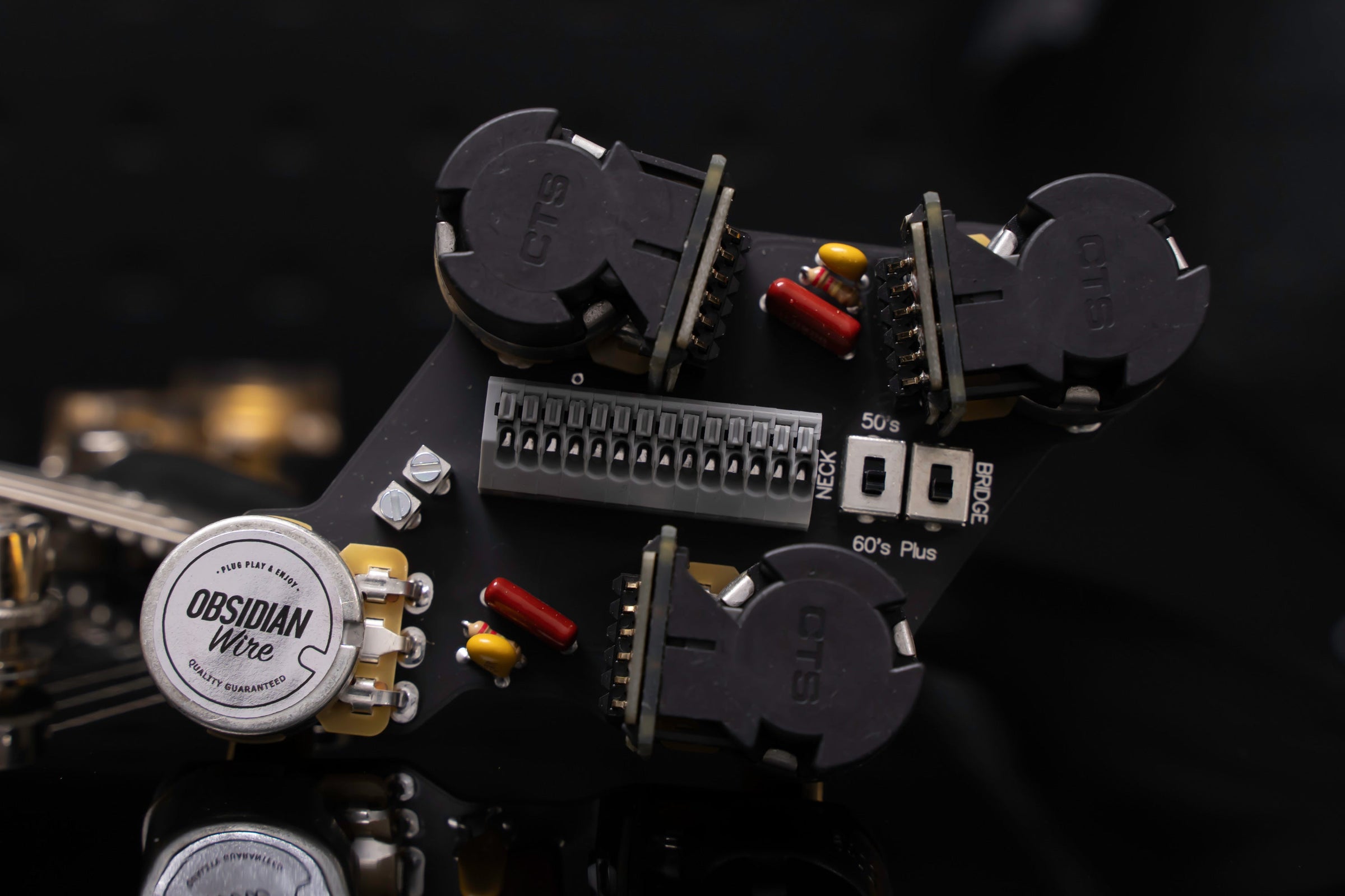 ObsidianWire Les Paul wiring harness with a blue Les Paul featuring gold knobs set as the background
