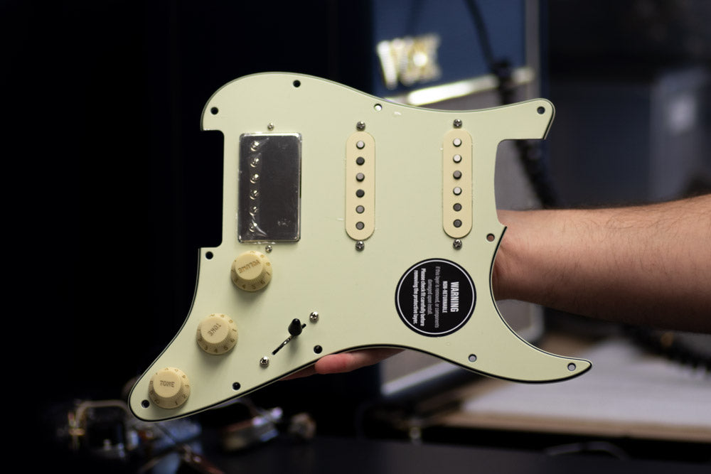 Obsidianwire custom HSS oaded pickguard for Stratocaster. The pickguard is mint green and the knobs and pickup covers are aged white