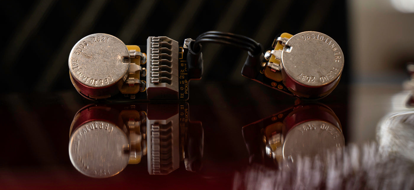 Close-up of a guitar pickup with metallic finish on a reflective surface.