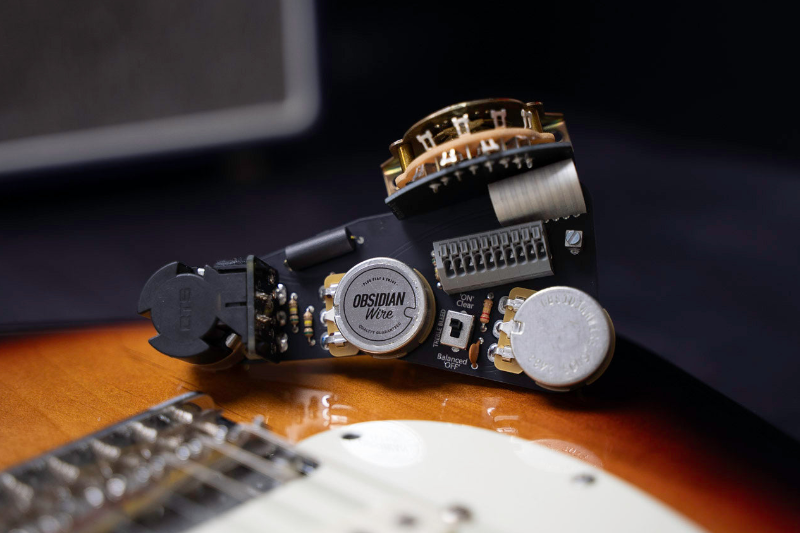 Guitar pickup and wiring on a guitar body with a dark background